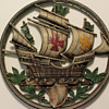A round cast metal wall hanging of a ship