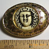 Golden colored brooch with white face