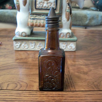 small brown square very detailed bottle with pointed metal screw on cap