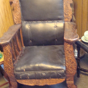 antique rocker with lion engravings and leather upholstry.