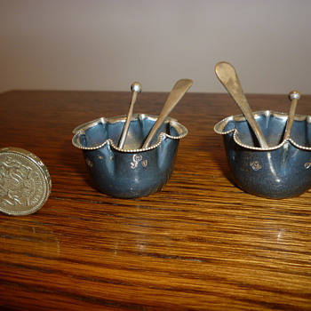 Antique British mustard bowls and ornate spoons.