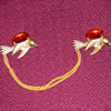 Sweater chain/pin with birds holding bronze-colored stones...