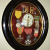 Old medals displayed in rounded glass frame.