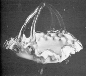 A Basket of Unusual Form: In this piece the exterior is a white opaque overlay and the interior rose opaque in color. The handle with double uprights and feet are of transparent amber glass. Height, 7/2 inches; width, 9 inches. A Basket of Unusual Form: In this piece the exterior is a white opaque overlay and the interior rose opaque in color. The handle with double uprights and feet are of transparent amber glass. Height, 7/2 inches; width, 9 inches.