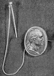 ILLUSTRATION I: A Berlin Casting Brooch: This brooch, with pin and chain, probably belonged originally to Mrs. Tobias Lear, niece of Mrs. Washington. It has a lock of the General's hair enclosed in the back. Size 14/16 by 10/16 inches. ILLUSTRATION I: A Berlin Casting Brooch: This brooch, with pin and chain, probably belonged originally to Mrs. Tobias Lear, niece of Mrs. Washington. It has a lock of the General's hair enclosed in the back. Size 14/16 by 10/16 inches.