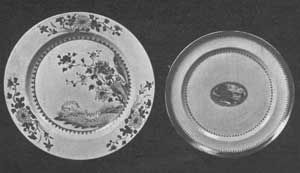 An Early and a Later Plate: At the left, a plate about 1760. The design in overglaze enamel shows a landscape with sheep, a European motif, with floral scrolls that are typically Chinese. The flowers in general are in pink and purple and the colors very clear. The glaze has a bluish tint. The plate on the right with small central medallion dates about 1820 and is typical of the later period of this ware. The medallion depicts an Occidental landscape. This and the narrow border are in a rust red with some gold. An Early and a Later Plate: At the left, a plate about 1760. The design in overglaze enamel shows a landscape with sheep, a European motif, with floral scrolls that are typically Chinese. The flowers in general are in pink and purple and the colors very clear. The glaze has a bluish tint. The plate on the right with small central medallion dates about 1820 and is typical of the later period of this ware. The medallion depicts an Occidental landscape. This and the narrow border are in a rust red with some gold.