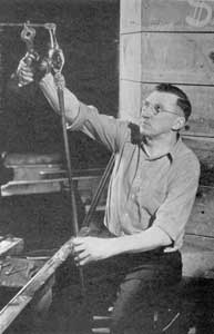 Applying the Stem: Here the gaffer, seated at his bench and using parrot shears, is steadying a gather of glass, as it is applied to the bulb with a pontil rod that will form the goblet stem. Applying the Stem: Here the gaffer, seated at his bench and using parrot shears, is steadying a gather of glass, as it is applied to the bulb with a pontil rod that will form the goblet stem.