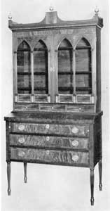 Illustration V: A Sheraton Secretary from Salem: The reeding of the legs, use of curly-maple veneer for the drawer fronts, and reeded pilasters framing the glasses of the doors, are evidences of the skill possessed by Salem craftsmen in the first decade of the 19th Century. Illustration V: A Sheraton Secretary from Salem: The reeding of the legs, use of curly-maple veneer for the drawer fronts, and reeded pilasters framing the glasses of the doors, are evidences of the skill possessed by Salem craftsmen in the first decade of the 19th Century.