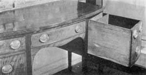ILLUSTRATION III: A Sideboard with Concealed Space: The deep drawer at the right has been pulled out to show the false back and additional space behind it. This might readily go unnoticed and provided a good hiding place for pieces of silver. ILLUSTRATION III: A Sideboard with Concealed Space: The deep drawer at the right has been pulled out to show the false back and additional space behind it. This might readily go unnoticed and provided a good hiding place for pieces of silver.