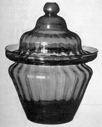 Illustration V: A Zanesville Sugar Bowl: Patterned in a bottle mold, this piece has expanded vertical ribbing, galleried rim, and double dome cover with ball finial. Similar bowls are known in clear, brilliant light green and greenish-yellow amber glass. Others, unpatterned, have been found in dark amber and green glass. Illustration V: A Zanesville Sugar Bowl: Patterned in a bottle mold, this piece has expanded vertical ribbing, galleried rim, and double dome cover with ball finial. Similar bowls are known in clear, brilliant light green and greenish-yellow amber glass. Others, unpatterned, have been found in dark amber and green glass.