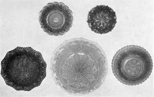 Five Plates of Various Sizes: Top row, left to right, plate of geometric design and diamond cutting in deep cobalt blue; plate with sunflower center against a stippled background, surrounded by a band of diamond cutting and prince's feather border in medium green. Lower row, left to right, plate with conventional foliage center and acanthus leaf border in light cobalt blue; center, plate with rayed center, a band of diamond cutting and bull's-eye border in delicate but fiery opalescent; right, twelve-sided plate with conventional rococo center and acanthus leaf border in deep cobalt blue. Five Plates of Various Sizes: Top row, left to right, plate of geometric design and diamond cutting in deep cobalt blue; plate with sunflower center against a stippled background, surrounded by a band of diamond cutting and prince's feather border in medium green. Lower row, left to right, plate with conventional foliage center and acanthus leaf border in light cobalt blue; center, plate with rayed center, a band of diamond cutting and bull's-eye border in delicate but fiery opalescent; right, twelve-sided plate with conventional rococo center and acanthus leaf border in deep cobalt blue.