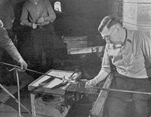 Freed from the Blow Pipe: Here the goblet, firmly attached to the pontil rod, has just been removed by the gaffer from the lower end of the blow pipe by a sharp blow preparatory to forming the upper part or bowl. Freed from the Blow Pipe: Here the goblet, firmly attached to the pontil rod, has just been removed by the gaffer from the lower end of the blow pipe by a sharp blow preparatory to forming the upper part or bowl.