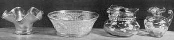 Illustration I: Imitation Favrile Glass and Pieces with Enameled Floral Decorations: The bowls at the left sought to imitate the fine Tiffany glass that its originator named "Favrile." The bowl and pitcher at the right are of light brown glass decorated with flowers in colored enamels. The pitcher has a handle that terminates in mid-air. Illustration I: Imitation Favrile Glass and Pieces with Enameled Floral Decorations: The bowls at the left sought to imitate the fine Tiffany glass that its originator named "Favrile." The bowl and pitcher at the right are of light brown glass decorated with flowers in colored enamels. The pitcher has a handle that terminates in mid-air.