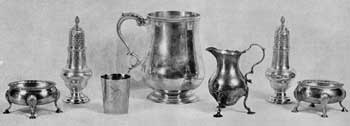 Large Pieces of Lear Silver: In the center a cann by Daniel Roger, Newport; at the left a small unmarked American cup; at the right cream pitcher by Samuel Meriton, London, circa 1750; at right and left, footed salt dishes and pepper shakers by David and Robert Hennell, London, 1769, and by an unknown London maker with mark I.D.-I.M. in Swiss cross. Large Pieces of Lear Silver: In the center a cann by Daniel Roger, Newport; at the left a small unmarked American cup; at the right cream pitcher by Samuel Meriton, London, circa 1750; at right and left, footed salt dishes and pepper shakers by David and Robert Hennell, London, 1769, and by an unknown London maker with mark I.D.-I.M. in Swiss cross.