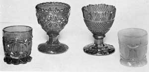 Night Nips and Egg Cups: Of two small rum cups in the foreground, that at the left, in emerald green, has a conventional design with stippling; while that at the right, in pale blue, has the same design without stippling. The egg cups are both of deep cobalt blue. That at the left has a design of leafage and diamond shapes; that at the right, with serrated upper edge, is a combination of stippling and diagonal ribbing in design. Night Nips and Egg Cups: Of two small rum cups in the foreground, that at the left, in emerald green, has a conventional design with stippling; while that at the right, in pale blue, has the same design without stippling. The egg cups are both of deep cobalt blue. That at the left has a design of leafage and diamond shapes; that at the right, with serrated upper edge, is a combination of stippling and diagonal ribbing in design.