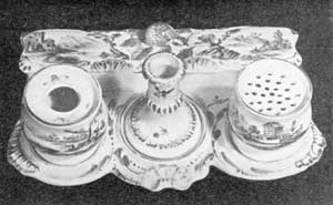Illustration IV: Porcelain Inkstand: Fashioned after the silver models made about 1740-1750, this specimen was made at Derby about 1760. It is simple in design and contains a sandbox, eliminated in the later models which became more ornate. Illustration IV: Porcelain Inkstand: Fashioned after the silver models made about 1740-1750, this specimen was made at Derby about 1760. It is simple in design and contains a sandbox, eliminated in the later models which became more ornate.
