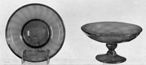 Illustration IV: Shallow Bowl and Small Compote: The bowl or pan with folded rim and expanded vertical ribbing is of golden amber glass. The compote has a bowl blown in a flask mold — ten diamonds — and applied stem and foot. Of brilliant deeper amber glass, it is attributed to Zanesville, Ohio. Illustration IV: Shallow Bowl and Small Compote: The bowl or pan with folded rim and expanded vertical ribbing is of golden amber glass. The compote has a bowl blown in a flask mold — ten diamonds — and applied stem and foot. Of brilliant deeper amber glass, it is attributed to Zanesville, Ohio.