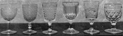 Six American Pattern Glass Goblets: From left to right the patterns are: Grape, collectible only in goblets; Diamond cut with Leaf; Paneled Daisy; Prism; Strawberry and Currant; and Honeycomb. Six American Pattern Glass Goblets: From left to right the patterns are: Grape, collectible only in goblets; Diamond cut with Leaf; Paneled Daisy; Prism; Strawberry and Currant; and Honeycomb.