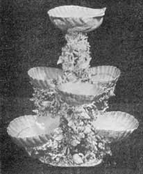 Illustration V: Sweetmeat Stand: This elaborate piece consists of three tiers of scallop shells supported by clusters of applied coral, small shells and seaweeds. Illustration V: Sweetmeat Stand: This elaborate piece consists of three tiers of scallop shells supported by clusters of applied coral, small shells and seaweeds.
