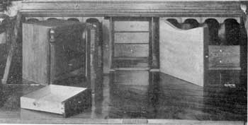 ILLUSTRATION II: The Hiding Places Revealed: The interior of this secretary. At the left is the central cabinet that has been removed. The door is partly open, showing its pigeonholes and drawer. The pilasters on both sides are firm. In the interior are shown the pair of document boxes and four small drawers concealed behind the cabinet. ILLUSTRATION II: The Hiding Places Revealed: The interior of this secretary. At the left is the central cabinet that has been removed. The door is partly open, showing its pigeonholes and drawer. The pilasters on both sides are firm. In the interior are shown the pair of document boxes and four small drawers concealed behind the cabinet.