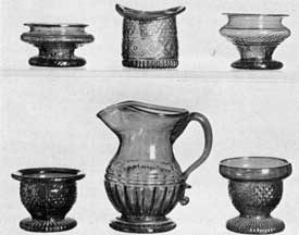 Illustration I: Well-Established Sandwich Patterns: All blown three-mold glass, in colors. The footed pitcher is in cobalt blue, as are the hat and the two salt dishes in the upper row. The salt dishes in the lower row are, left, deep amethyst; right, sapphire blue. Illustration I: Well-Established Sandwich Patterns: All blown three-mold glass, in colors. The footed pitcher is in cobalt blue, as are the hat and the two salt dishes in the upper row. The salt dishes in the lower row are, left, deep amethyst; right, sapphire blue.
