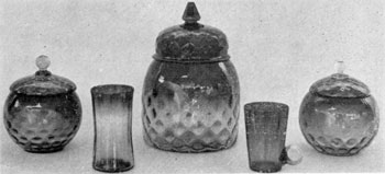 8. Pair of sweetmeat jars, a cracker jar, a tumbler and a mug in Amberina glass. The shading is from light amber to ruby red. The jars, molded and blown in an Inverted Thumbprint pattern, possibly were made by the New England Glass Company after 1883. 8. Pair of sweetmeat jars, a cracker jar, a tumbler and a mug in Amberina glass. The shading is from light amber to ruby red. The jars, molded and blown in an Inverted Thumbprint pattern, possibly were made by the New England Glass Company after 1883.