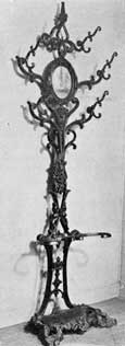 Hat Rack of Cast-Iron: Like those of wood this is complete with central mirror. The design combines conventional scales with touches of Gothic Revival. Such pieces of furniture are less seldom found than chairs and benches but were popular in their time. Hat Rack of Cast-Iron: Like those of wood this is complete with central mirror. The design combines conventional scales with touches of Gothic Revival. Such pieces of furniture are less seldom found than chairs and benches but were popular in their time.