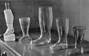 Illustration III: Boots and Shoes in Glass: The three at the right are boots in clear glass. The largest, center, is 10 1/4 inches high. The one at the extreme left, which is a bottle, has a frosted finish. Its base is a hassock. It has a total height of twelve inches. Illustration III: Boots and Shoes in Glass: The three at the right are boots in clear glass. The largest, center, is 10 1/4 inches high. The one at the extreme left, which is a bottle, has a frosted finish. Its base is a hassock. It has a total height of twelve inches.