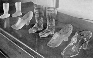 Illustration VI: More Boots and Slippers: Of the two high boots in the center, that at left has a view of Hamburg at the top of the leg. The slippers at the right are rarities as are the smaller frosted boots at the extreme left. Illustration VI: More Boots and Slippers: Of the two high boots in the center, that at left has a view of Hamburg at the top of the leg. The slippers at the right are rarities as are the smaller frosted boots at the extreme left.
