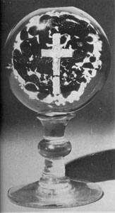 Millville Paperweight Mounted On Goblet-like Base: Here the central figure is a sulphide crucifix and the background is of mottled green and brown glass. This was originally made as a flat paperweight and the footed base was developed later. Millville Paperweight Mounted On Goblet-like Base: Here the central figure is a sulphide crucifix and the background is of mottled green and brown glass. This was originally made as a flat paperweight and the footed base was developed later.