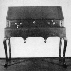 Illustration II: Queen Anne Desk on Frame: Made about 1720, the writing lid folds outward and rests on sliding bracket supports. The finials of the apron are reminiscent of the earlier period of William and Mary. Illustration II: Queen Anne Desk on Frame: Made about 1720, the writing lid folds outward and rests on sliding bracket supports. The finials of the apron are reminiscent of the earlier period of William and Mary.
