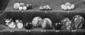 The Chief Varieties of Old American Marbles: Upper row, group 1, glazed pottery marbles; group 2, small stone marbles; and group 3, typical ones of clay with striped colored decoration. Lower row, group A-1, four glass examples with sulphide centers in the form of animals; A-2, a marble made of slag glass; A-3, two of pottery with colorful glazed decoration, one mottled, the other in a swirled effect simulating those of glass; A-4, one of amber glass flacked with gold; and A-5, three large marbles of clear glass where decoration was accomplished by spiral twisting of threads of colored glass in the process of manufacture. The Chief Varieties of Old American Marbles: Upper row, group 1, glazed pottery marbles; group 2, small stone marbles; and group 3, typical ones of clay with striped colored decoration. Lower row, group A-1, four glass examples with sulphide centers in the form of animals; A-2, a marble made of slag glass; A-3, two of pottery with colorful glazed decoration, one mottled, the other in a swirled effect simulating those of glass; A-4, one of amber glass flacked with gold; and A-5, three large marbles of clear glass where decoration was accomplished by spiral twisting of threads of colored glass in the process of manufacture.