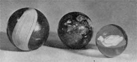 Three Marbles of Early American Make: At the left, one of opaque black glass with surface decoration. In the center a mottled pottery marble in colorings like the Bennington ware which copied that made at the Rockingham pottery. At the right an excellent example of a clear glass marble with silver-like sulphide center in the shape of a water fowl. Three Marbles of Early American Make: At the left, one of opaque black glass with surface decoration. In the center a mottled pottery marble in colorings like the Bennington ware which copied that made at the Rockingham pottery. At the right an excellent example of a clear glass marble with silver-like sulphide center in the shape of a water fowl.