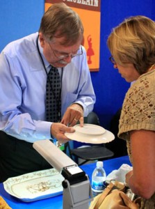 Gallery director of Cincinnati Art Galleries, Riley Humler shows a guest the maker's mark on a piece of Haviland china at the Pottery & Porcelain table. Gallery director of Cincinnati Art Galleries, Riley Humler shows a guest the maker's mark on a piece of Haviland china at the Pottery & Porcelain table.