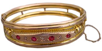 A hinged, 9-karat yellow gold bangle with gypsy set garnets and diamonds, from Chester England, 1907. A hinged, 9-karat yellow gold bangle with gypsy set garnets and diamonds, from Chester England, 1907.
