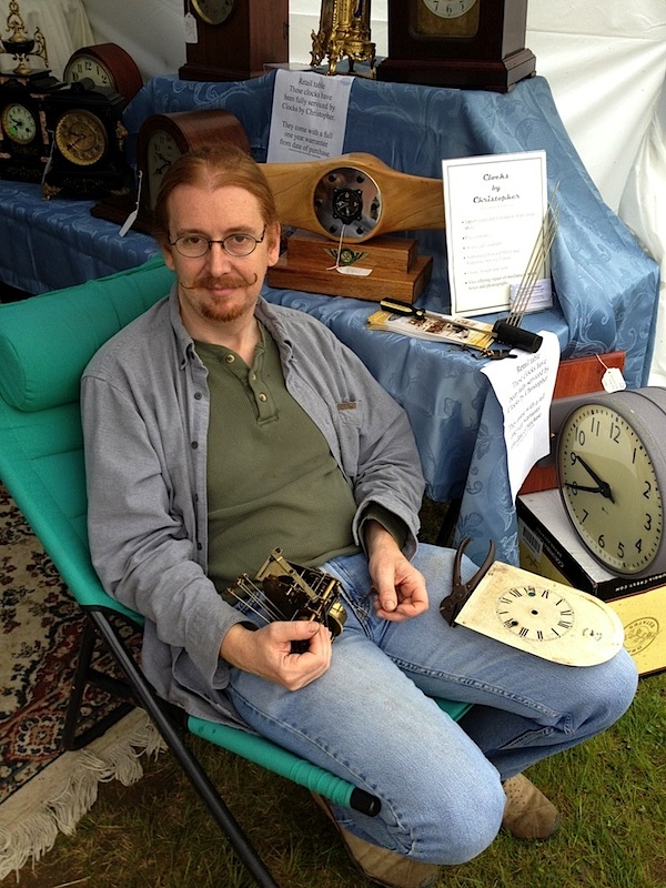 Clocks_by_Christopher Christopher, who restores antique timepieces, is shown manning his ClocksByChristopher.com booth at the May Brimfield. Photo by Ben Marks.