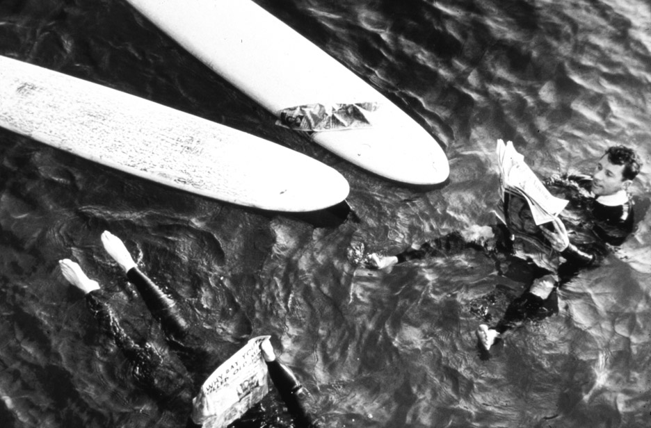 guys-in-water O'Neill and another surfer demonstrate the immense benefit of wetsuits by leisurely reading the paper at sea.