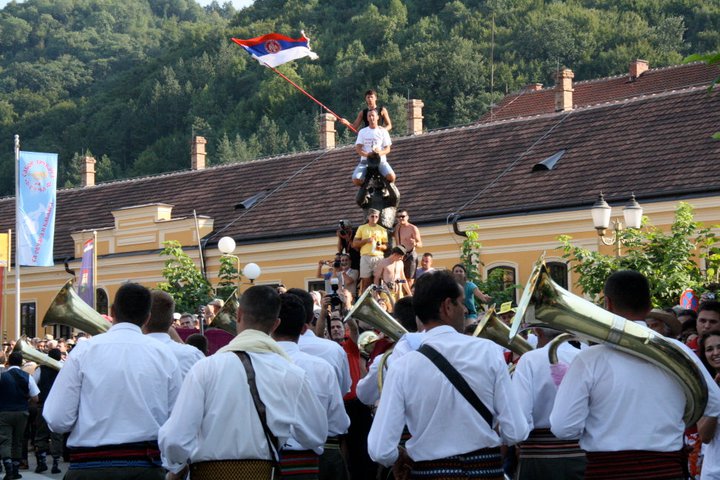 statue flag Demiran Ćerimović Orchestra approaches a flag-waver on a statue. The Guča Trumpet Festival is a big source of national pride, hence its not uncommon to see attendees waving the Serbian flag. (Still from “Brasslands” courtesy of the Meerkat Media Collective)