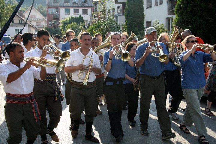 zu_cerimovic Top: Brass bands play anywhere and everywhere during the Guča Trumpet Festival, and the crowds love it. (Still from “Brasslands” courtesy of the Meerkat Media Collective) Above: Demiran Ćerimović and his orchestra play with the American band Zlatne Uste in the streets. (Via the "Brasslands" Facebook page)