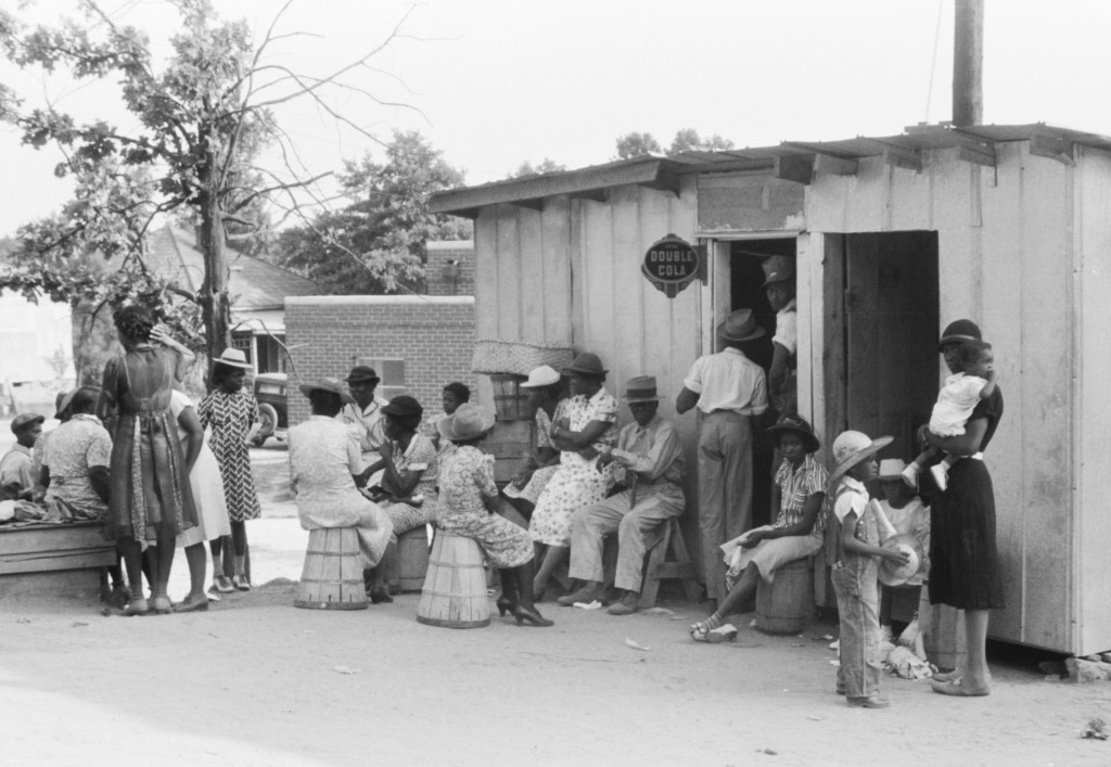 A crowd gathers outside a store and barbershop in Union Point, Georgia, circa 1941. Photo by Jack Delano, via the Library of Congress.