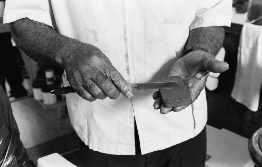 Louis McDowell demonstrates how to sharpen a straight razor at his shop in Paterson, New Jersey, in 1994. Via the Library of Congress.