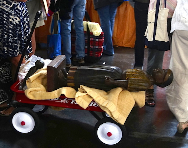 roadshow_statue Large and small statues ride on a blanket in a Radio Flyer wagon as their owner waits in line.