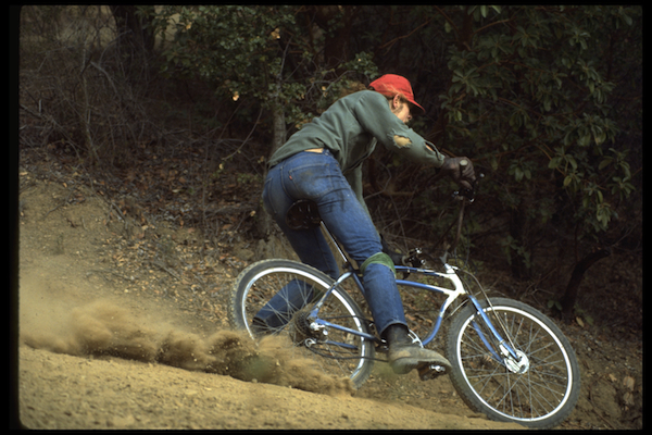 Charlie Kelly skidding around Camera Corner on a blue-and-white Schwinn Excelsior.