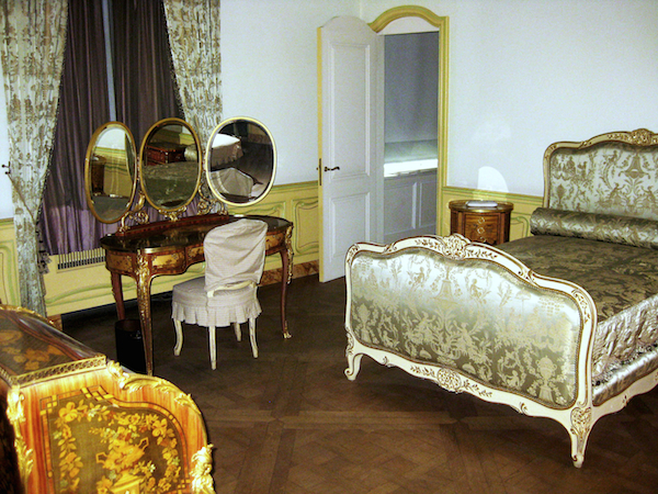 huguette_bedroom A bedroom inside Huguette Clark's apartment. In the 1990s, Huguette Clark commissioned exact replicas of all her mother's Victorian bedroom furniture including a gray-painted and parcel-gilt bed upholstered in Chinoserie-patterned silk damask, a French ormolu-mounted tulipwood, bois satine, sycamore, and fruitwood marquetry and parquetry dressing table with three folding oval mirrors, and a French ormolu-mounted tulipwood, sycamore, and stained fruitwood marquetry and parquetry bureau a cylindre. (Via the estate of Huguette Clark from EmptyMansionsBook.com)