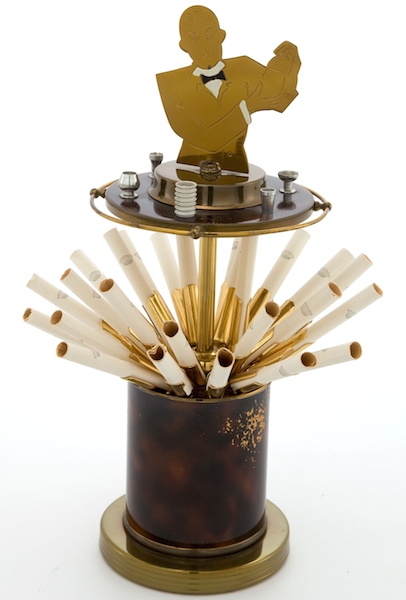 Mantique-edit_AN ART DECO BRASS AND BAKELITE BARTENDER-FORM CIGARETTE DISPENSER This Art Deco brass cigarette dispenser, featuring a bartender on top, is filled with cigarette holders. (Via "Mantiques")