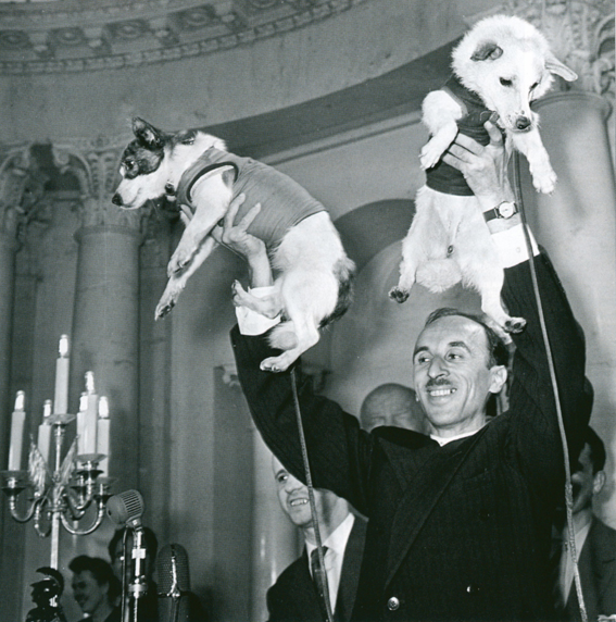 Soviet space researcher Oleg Gazenko holds Strelka (left) and Belka (right) aloft at the 1960 press conference immediately after their landing. In his memoirs, Gazenko referred to this as the proudest moment of his life. (© FUEL Publishing)