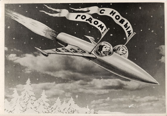 A 1960 USSR postcard showing Belka and Strelka in their rocket by the photomontage artist Sveshnikov. The flags read, "Happy New Year," the wing of the rocket reads, "‘USSR," and inside the cockpits, it says, "Strelka" and "Belka." (© FUEL Publishing)