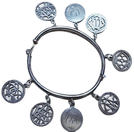 This silver hinged bangle features six love tokens with cut-out ovelapping initials and two with engraved linear initials. (Courtesy of the Love Token Society)