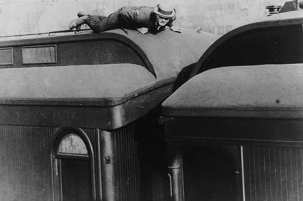 A man lying prone atop a railroad passenger car in a 1907 photo titled, "Tramp life—how Jack London traveled on a passenger coach." (From the Bain Collection, Library of Congress)