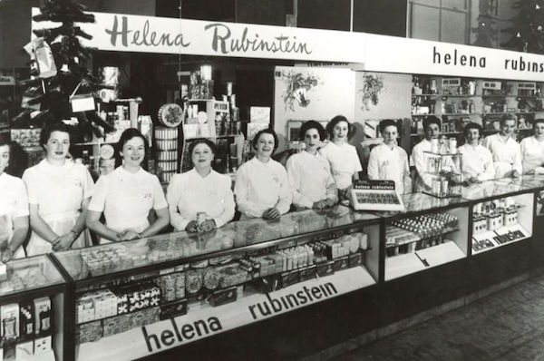 Saleswomen in uniforms line a Helena Rubinstein makeup counter. (© Helena Rubinstein, Inc.)